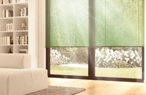 Teil eines Wohnzimmers mit bodenhohen Fenstern mit grünen Jalousien