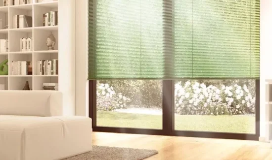 Teil eines Wohnzimmers mit bodenhohen Fenstern mit grünen Jalousien